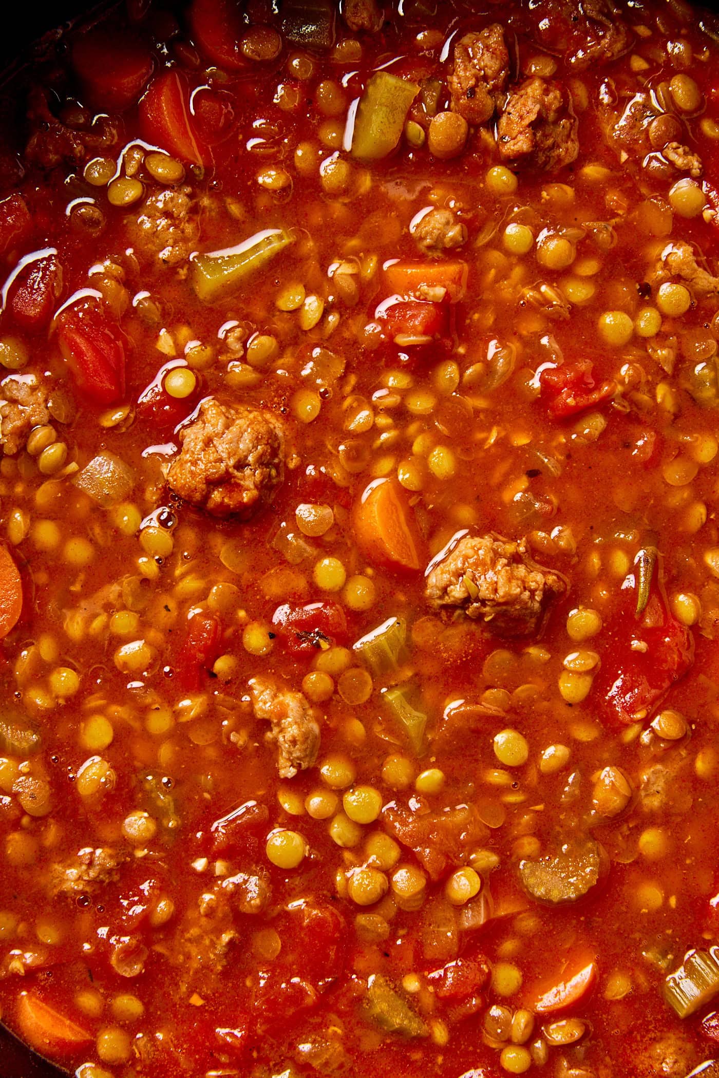 Sausage and lentil soup in a pot full of soup.