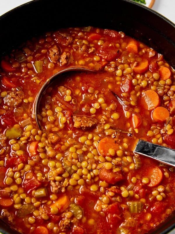 Sausage and lentil soup in a pot with a ladle.