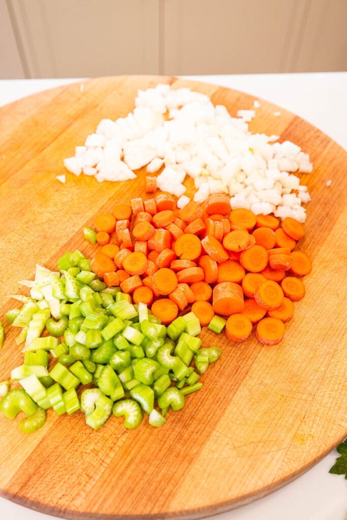 Chopped celery, carrot, and onion on a cutting board.
