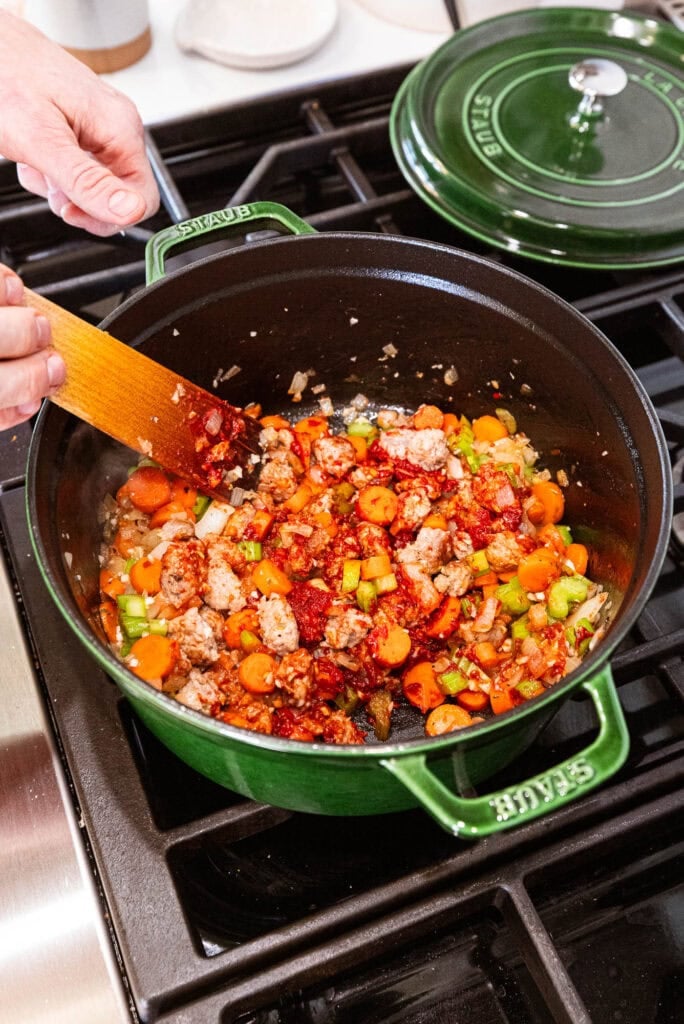 Cooking tomato paste with the vegetables and sausage.