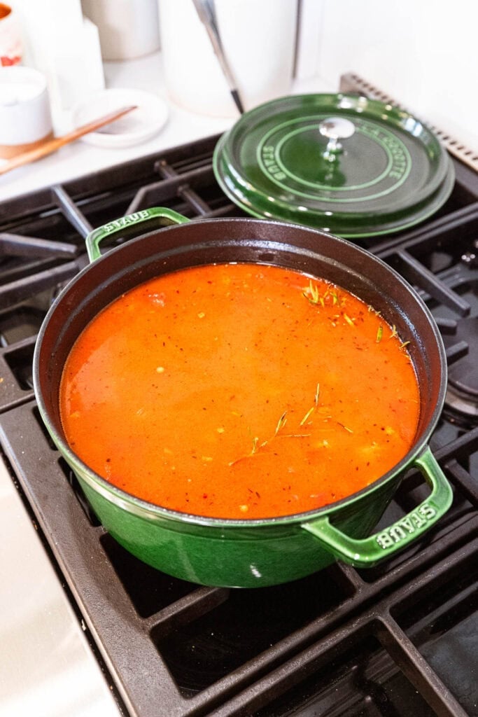 Sausage and lentil soup simmers over the stove with a sprig of rosemary.