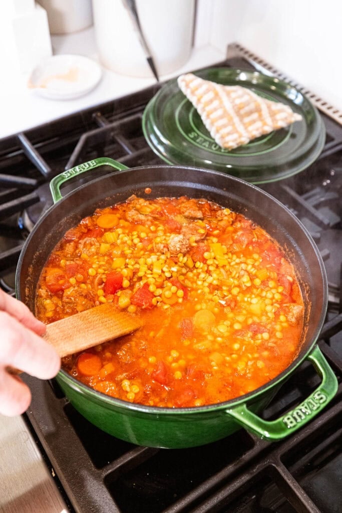 Cooked sausage and lentil soup cooks on a stove.