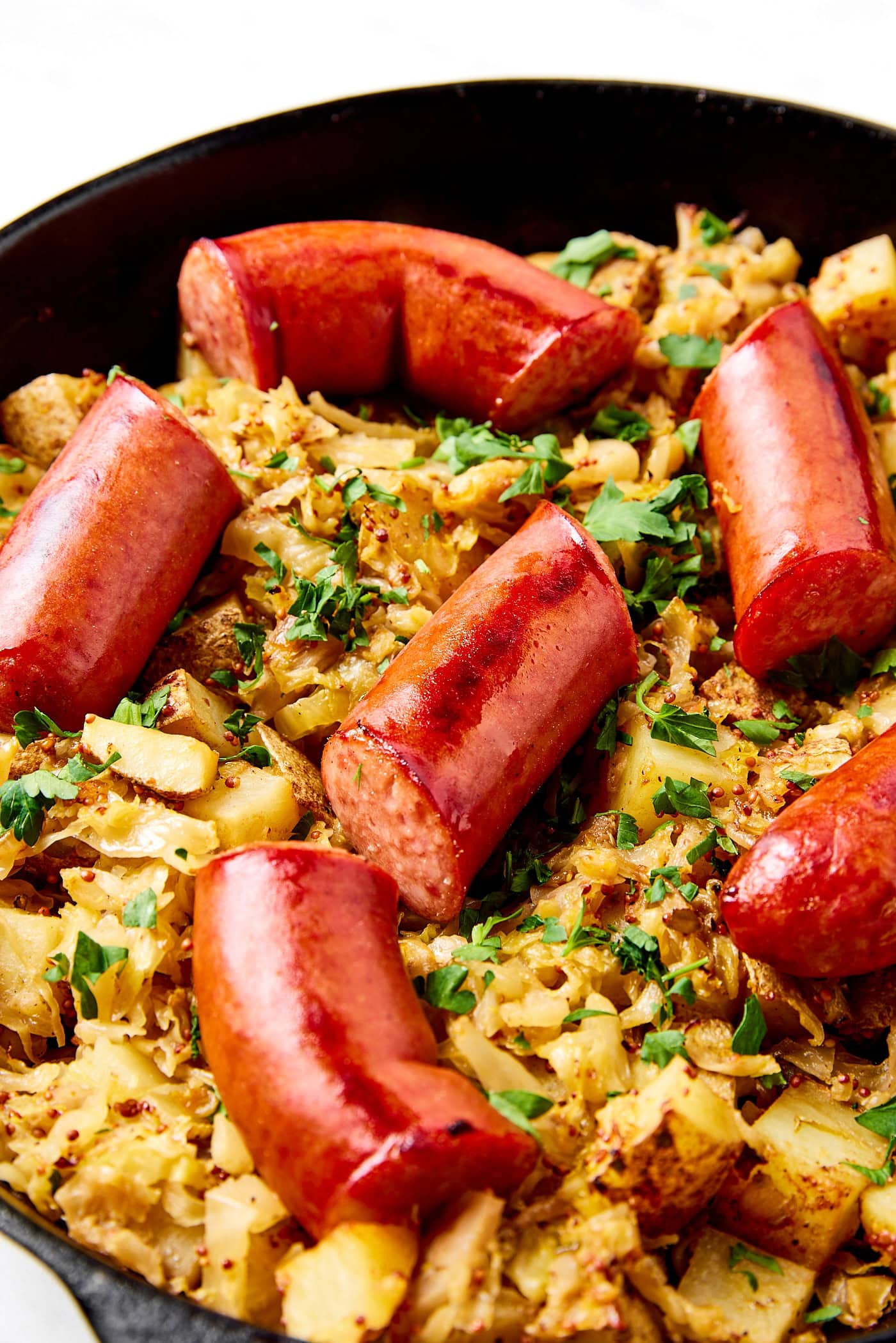 Kielbasa sits on a layer of sauerkraut and potatoes.