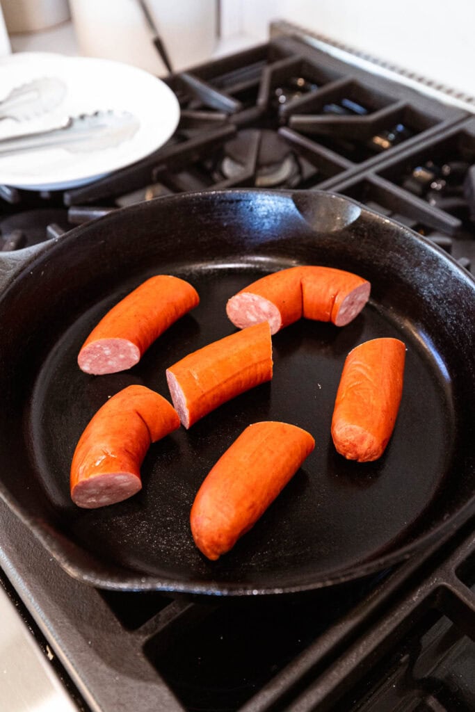 Kielbasa begins to brown in an iron skillet over heat.