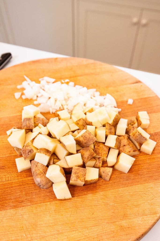 Diced potatoes and onions on a cutting board.