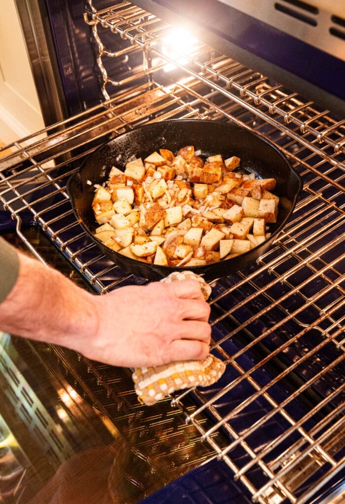 Placing potatoes and onions in an oven to roast.