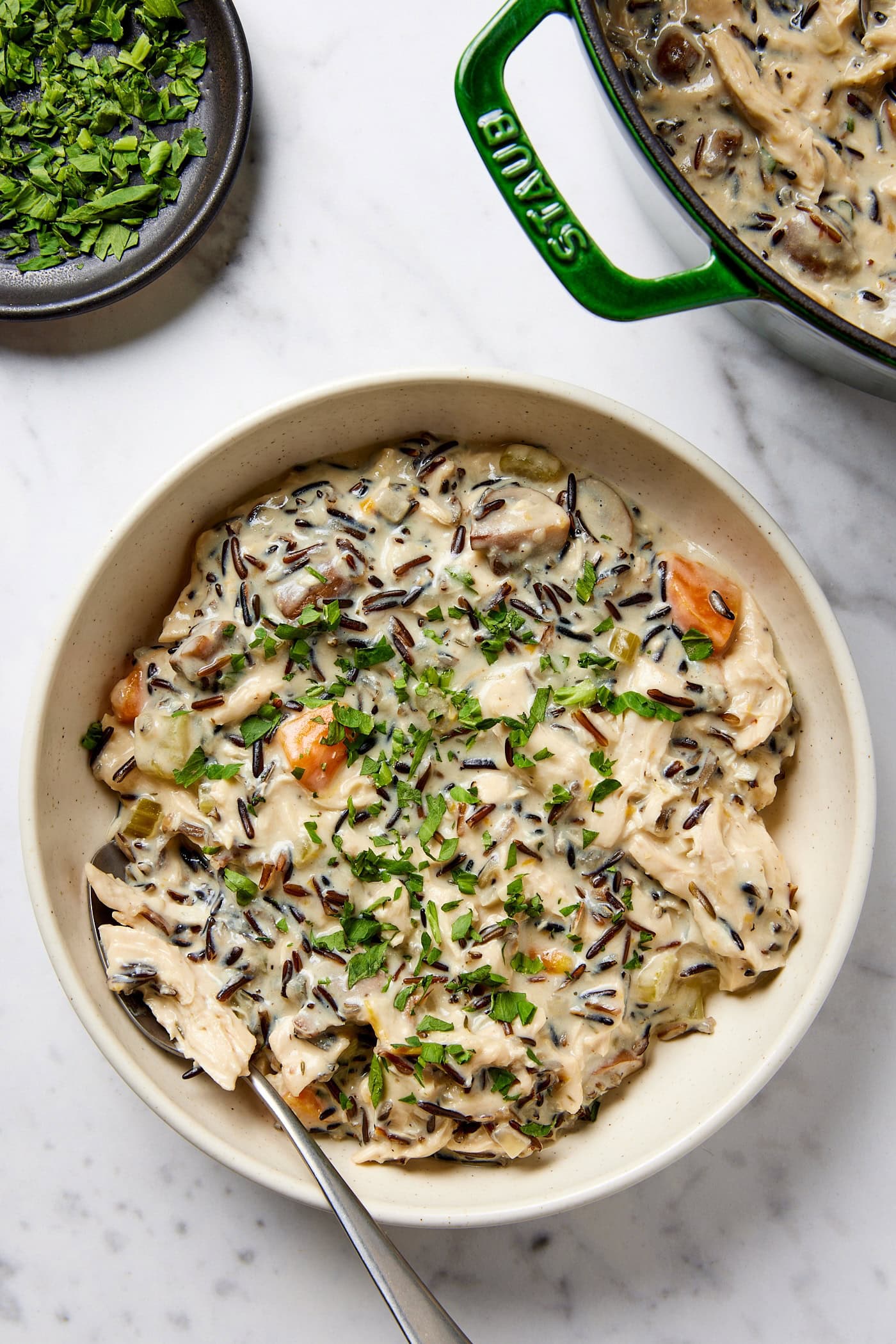 A bowl of chicken and wild rice soup garnished with chopped celery leaves.