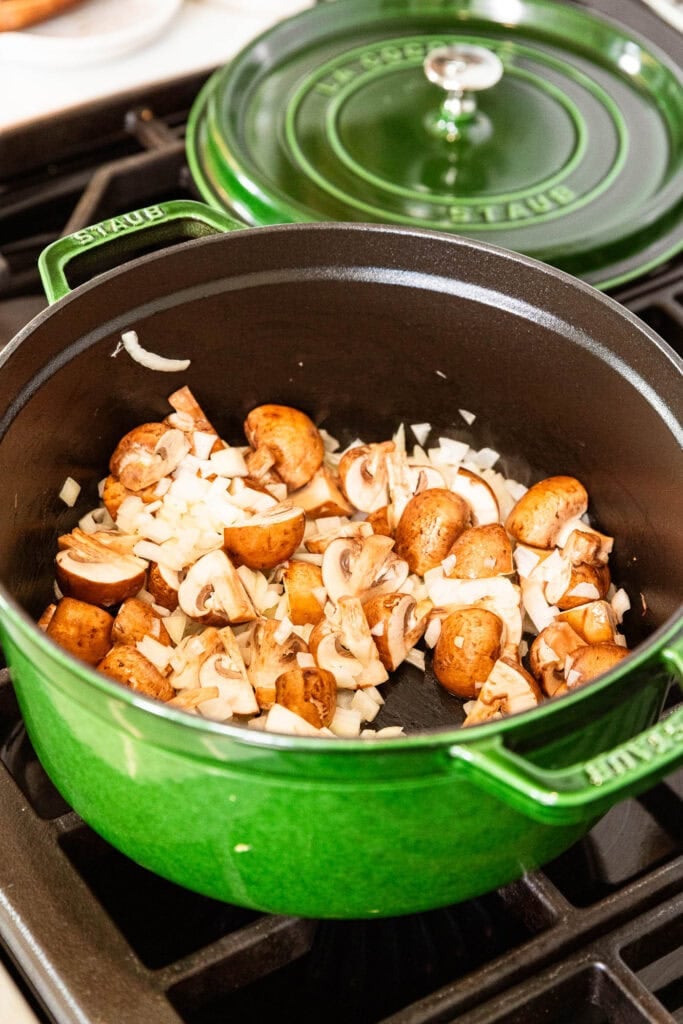 Mushrooms and onion sauté in a pot.
