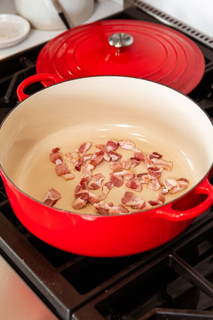 Bits of bacon in a pot browning in a pot.