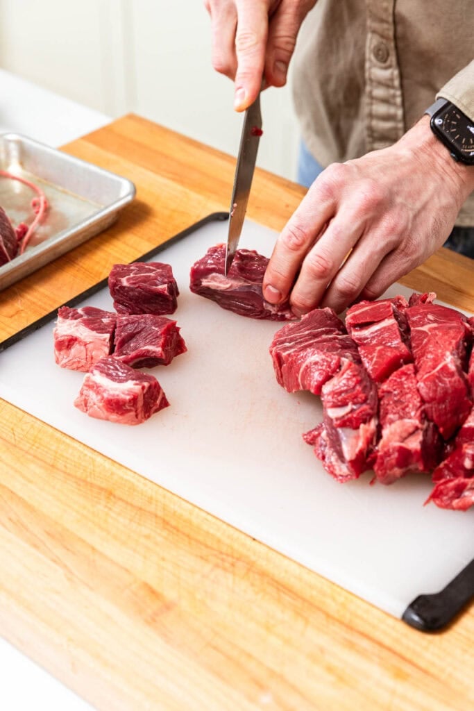 Cubing beef chuck roast prior to cooking.