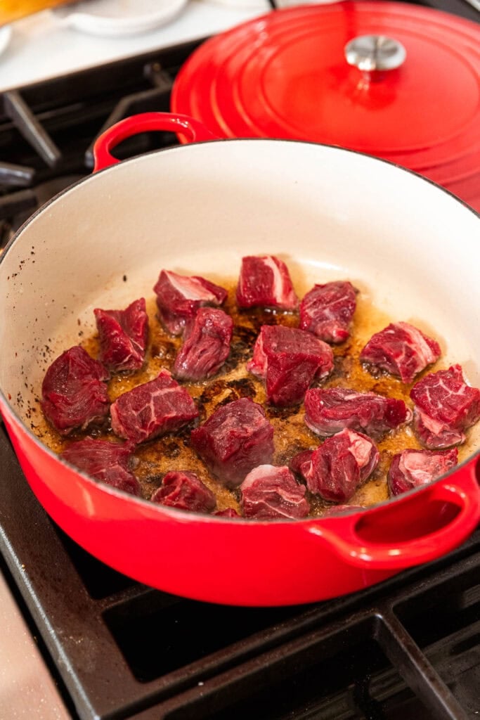 Cubes of beef brown slightly in a pot.