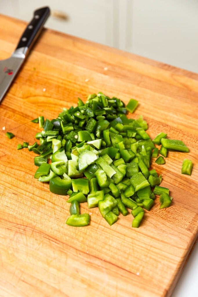 Chopped green pepper on a wooden cutting board.