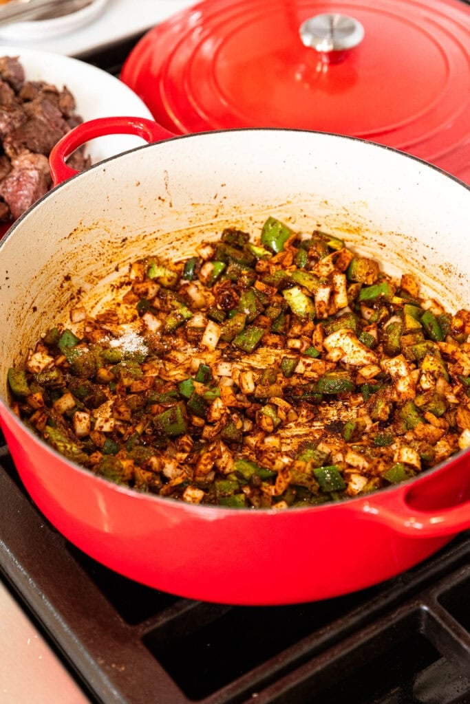 Onion, bell pepper, and jalapeño soften in a pot.