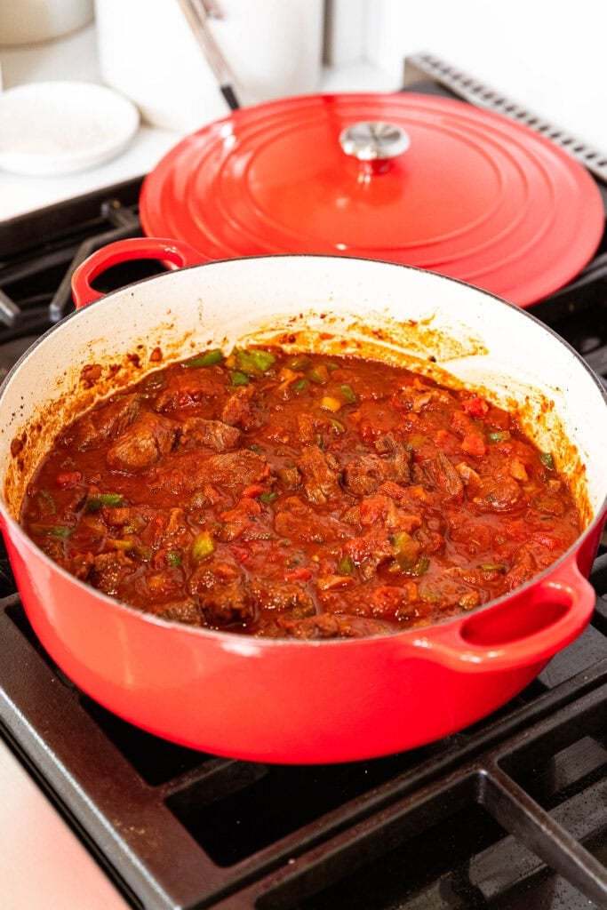 Chili ingredients added to a pot begin to cook down.
