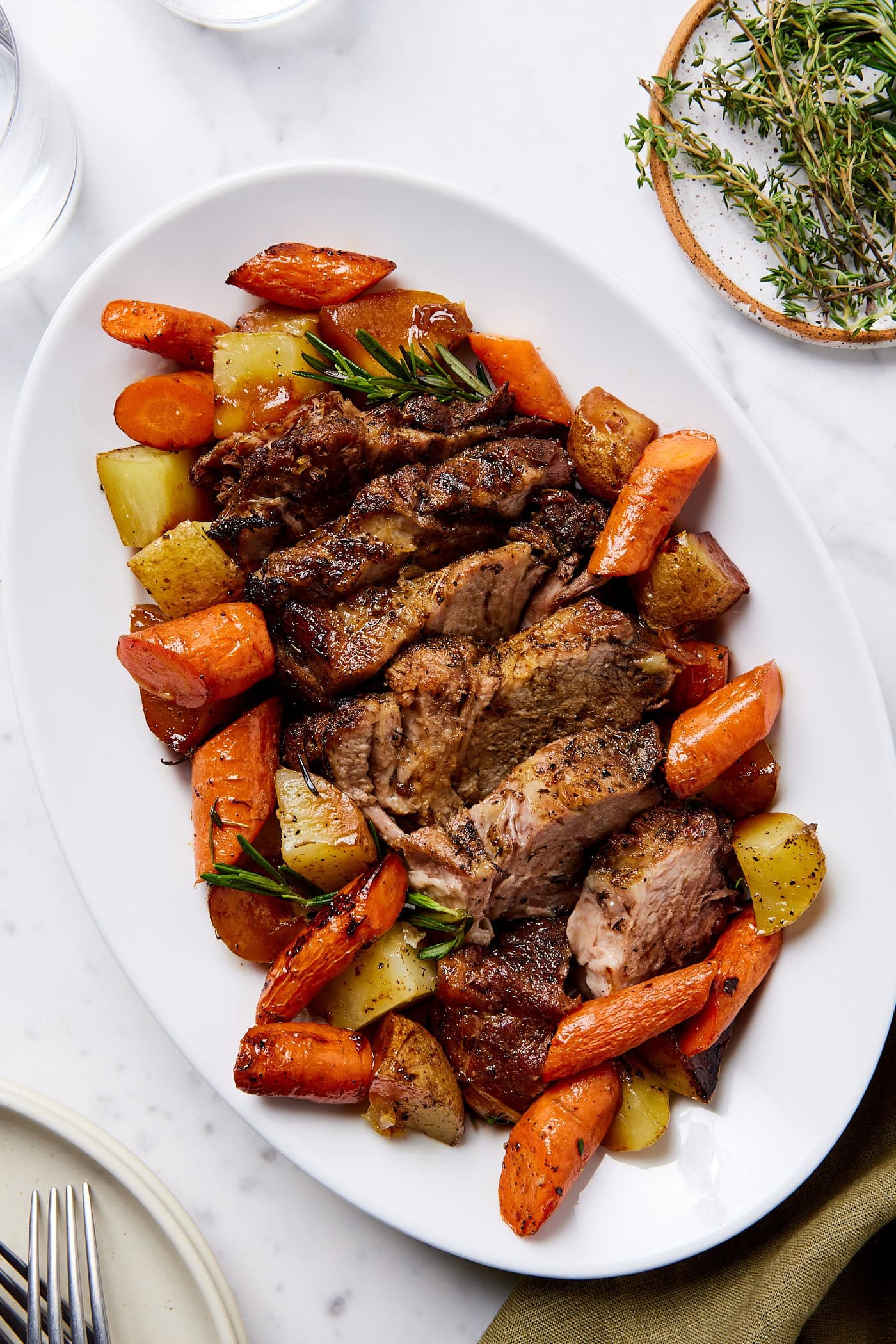 Slices of pork roast surrounded by carrots and potatoes on a plate.