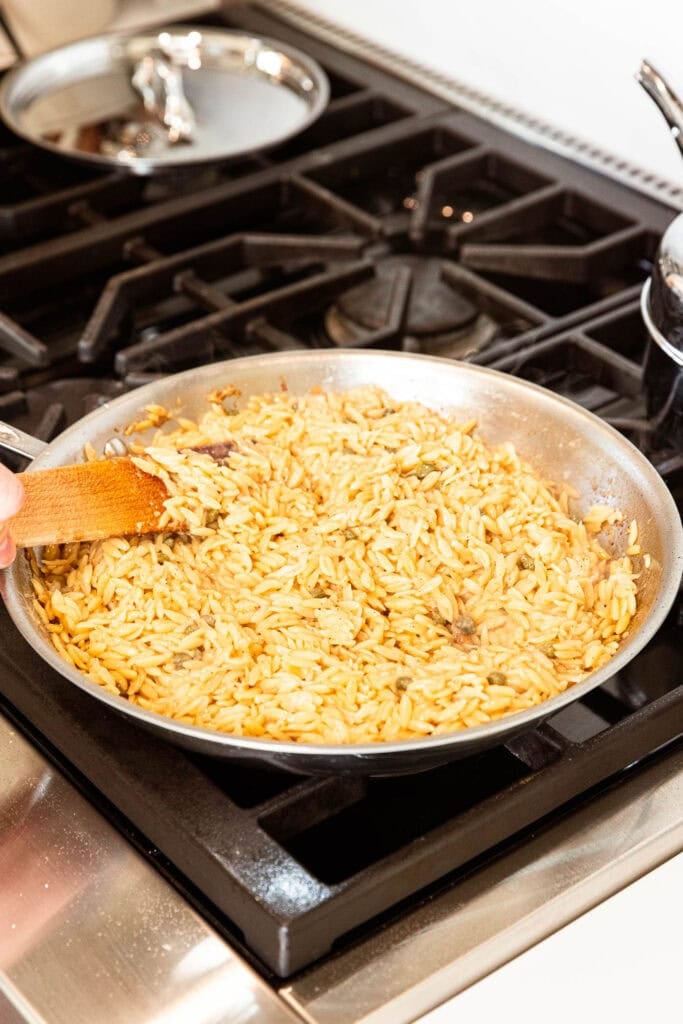 Cooked orzo with capers on the stove.