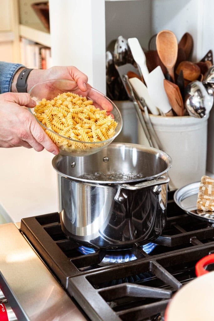Adding pasta noodles to a boiling pot of water.