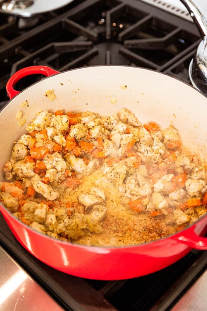 Cooking diced chicken and vegetables in a pot.
