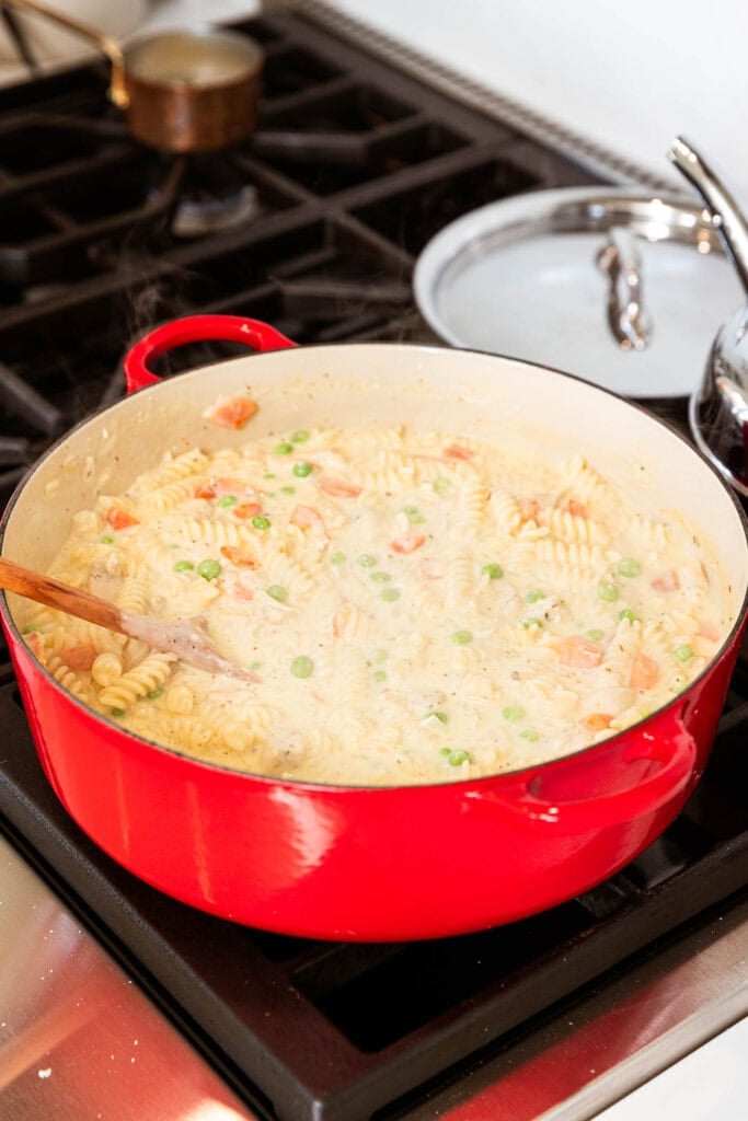 Adding noodles to complete the chicken pot pie casserole.