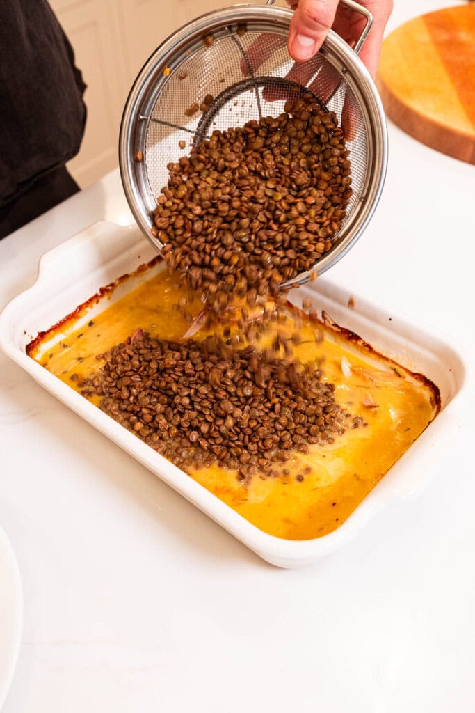 Adding lentils to a honey mustard sauce in a baking dish.