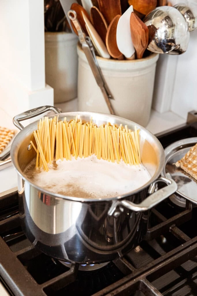 Noodles begin to cook in a pot of boiling water.