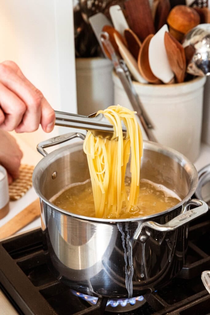 Noodles get removed from a pot after cooking.