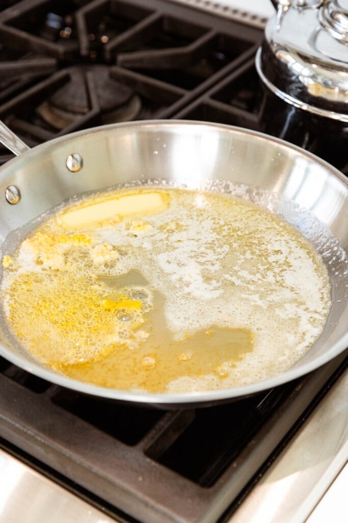 Butter melts in a saucepan with lemon zest and garlic.