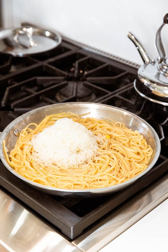 A pile of freshly grated cheese begins to melt into lemon butter pasta.