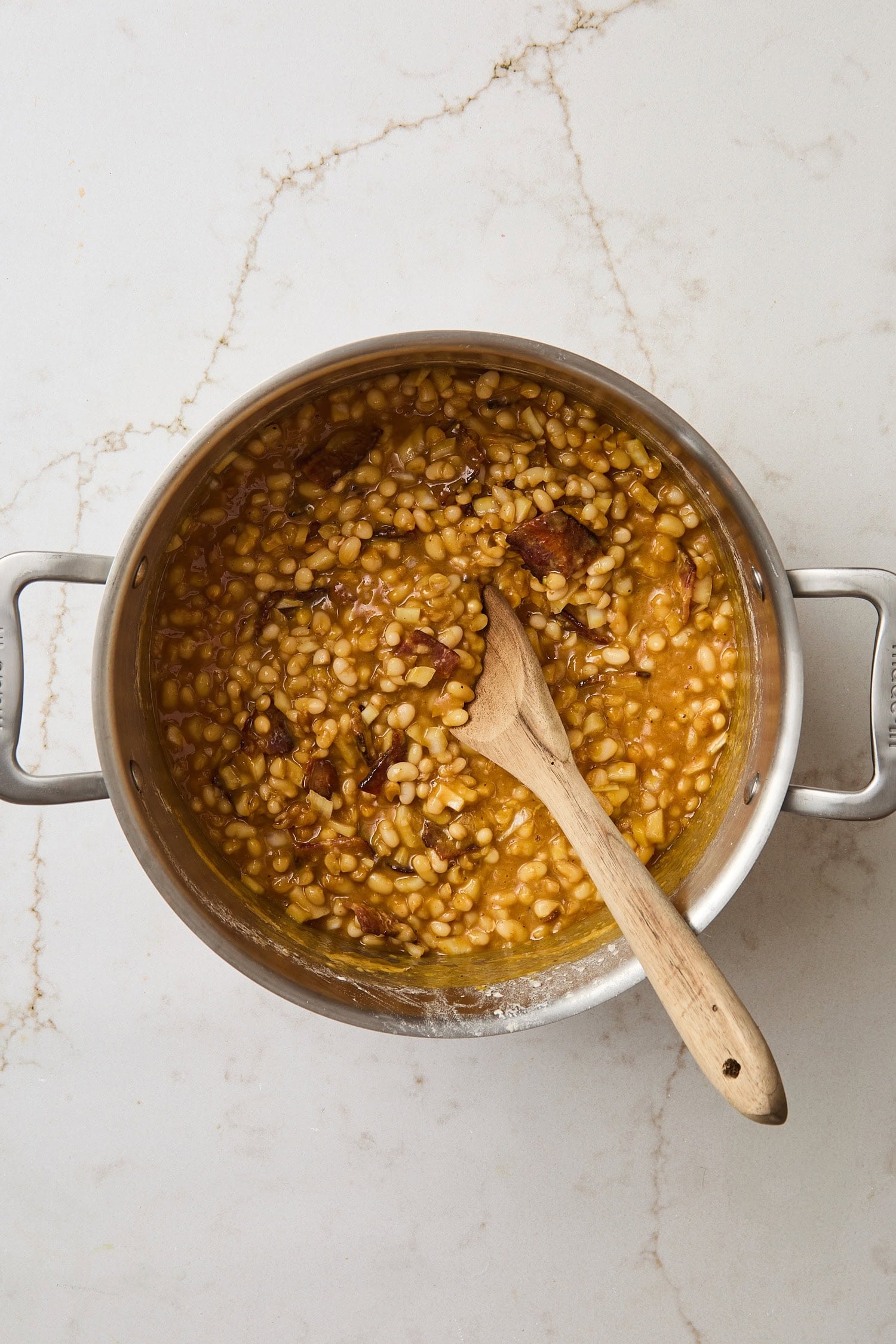 Saucepan filled with mixture of baked beans before being put in the oven.