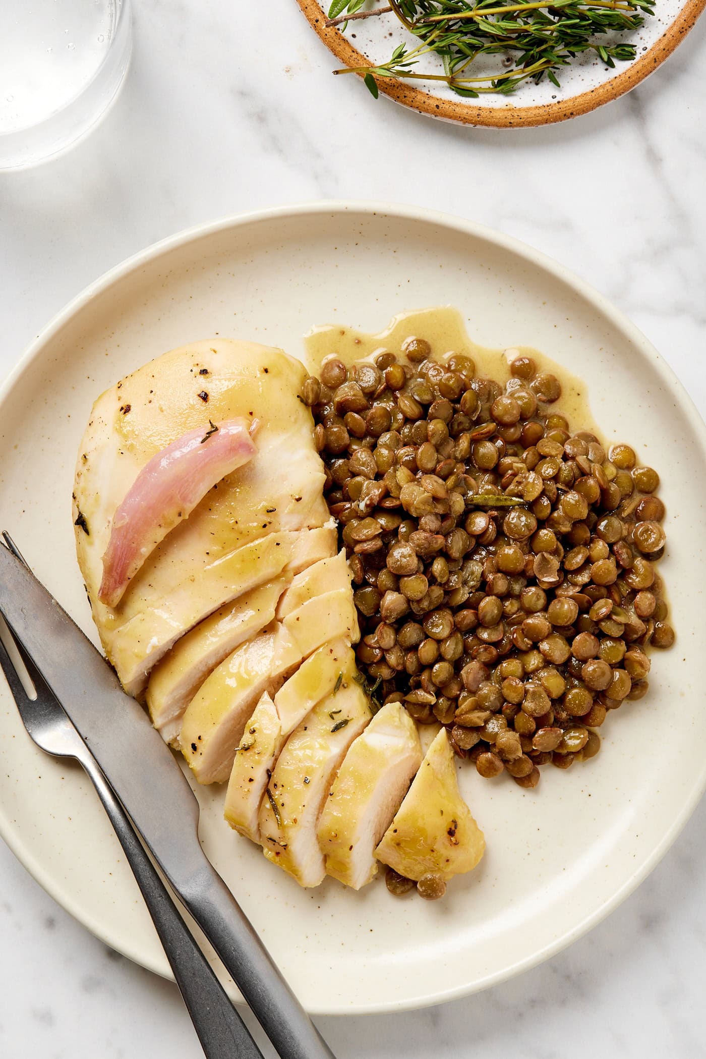 Sliced honey mustard chicken breast next to lentils.