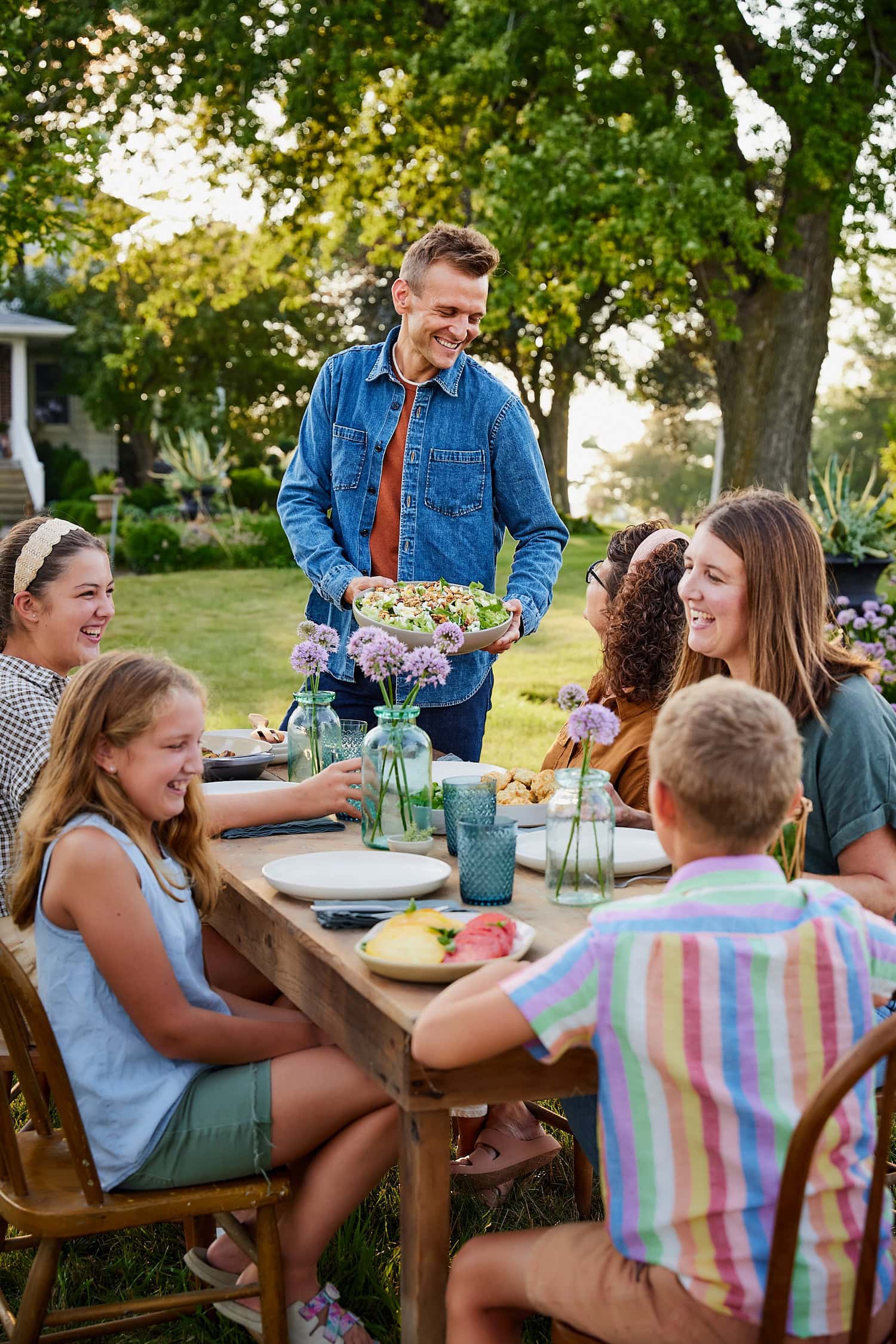 Kaleb Wyse serving at a table filled with people during a summer evening.