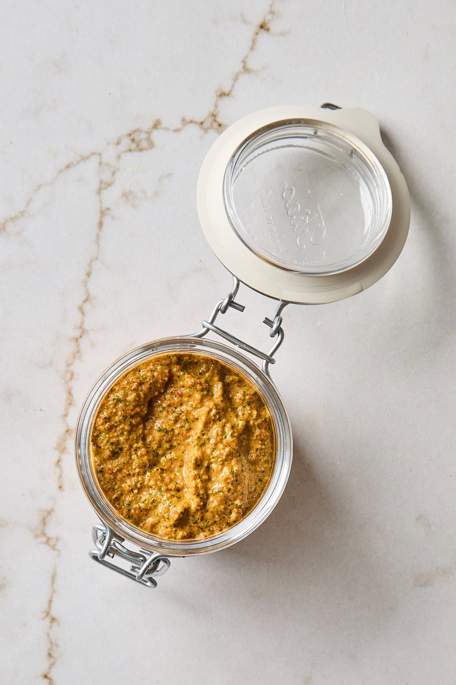 Glass container filled with arugula pesto after being blended.