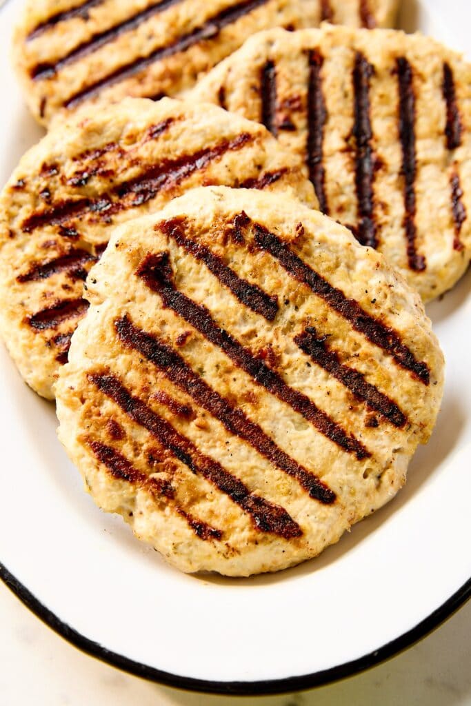 Grilled chicken burgers on a white platter.