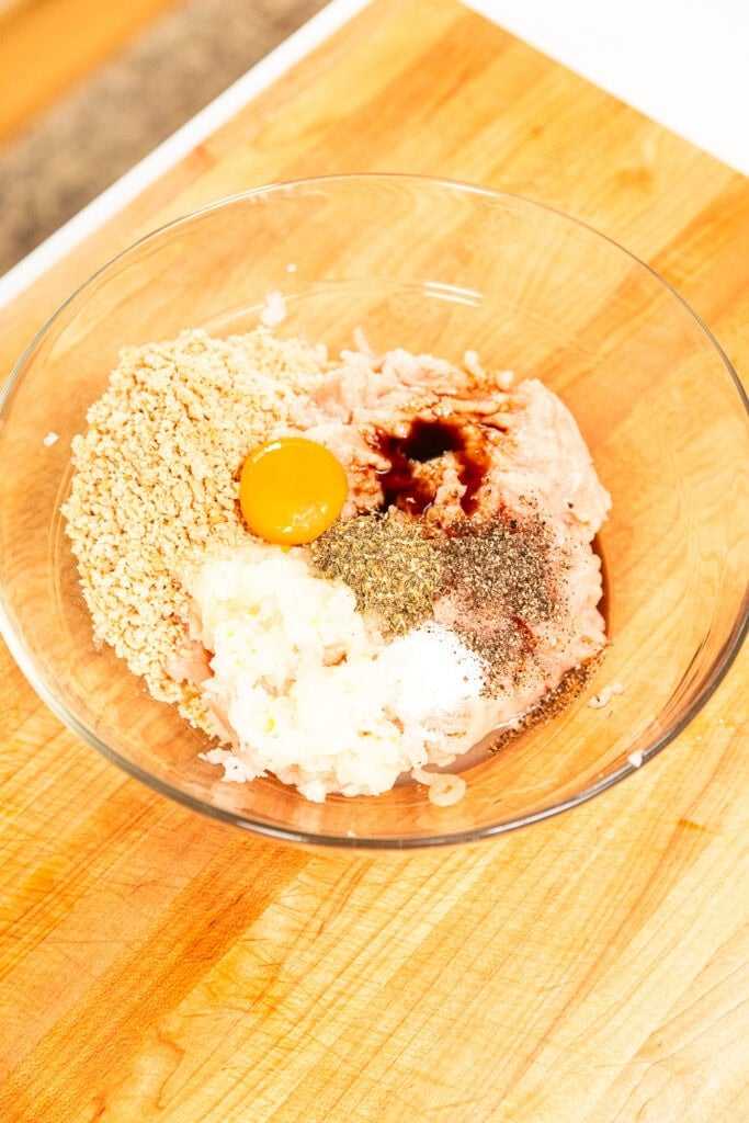Ingredients to make a chicken burger in a glass bowl.