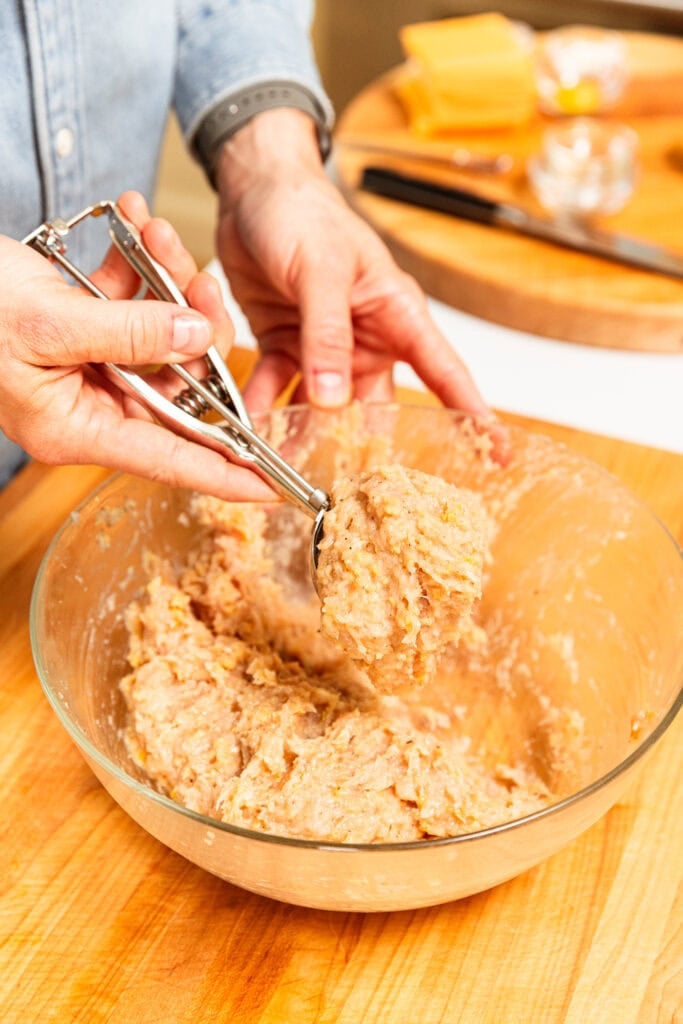Scooping out ground chicken mixture to form burger patties.