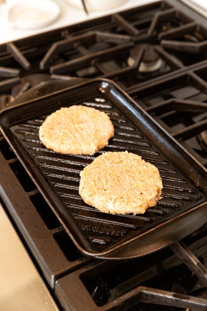 Chicken patties cooking on a grill pan.