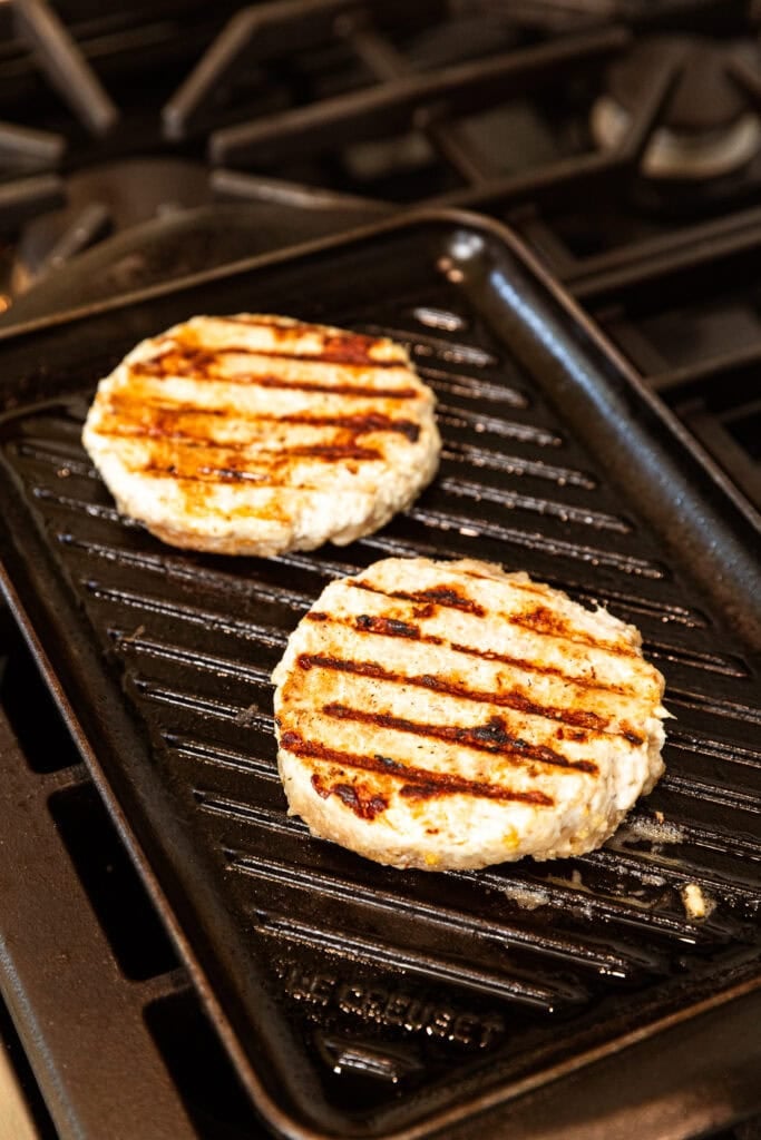 Cooked chicken burgers on a grill pan.