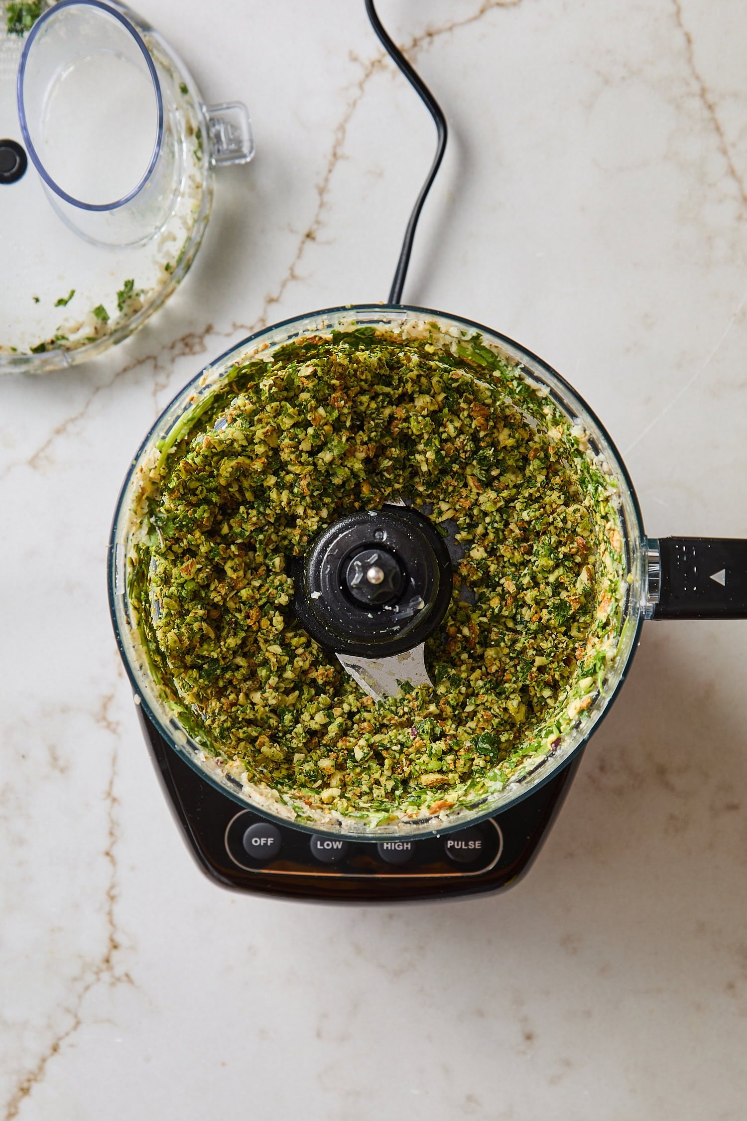 Food processor with blended mixture for cilantro pesto.