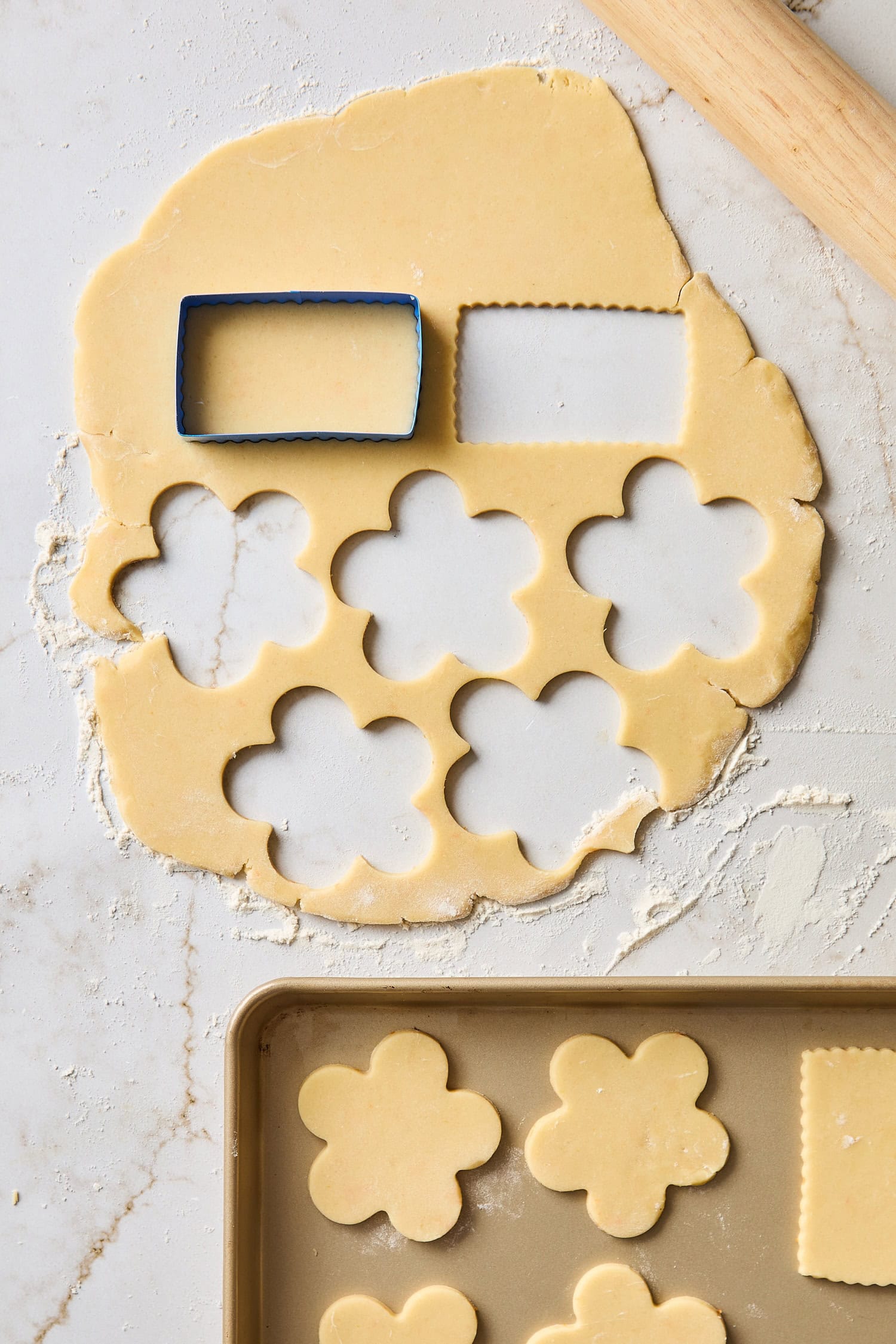 Sugar cookies being cut from dough before being baked.