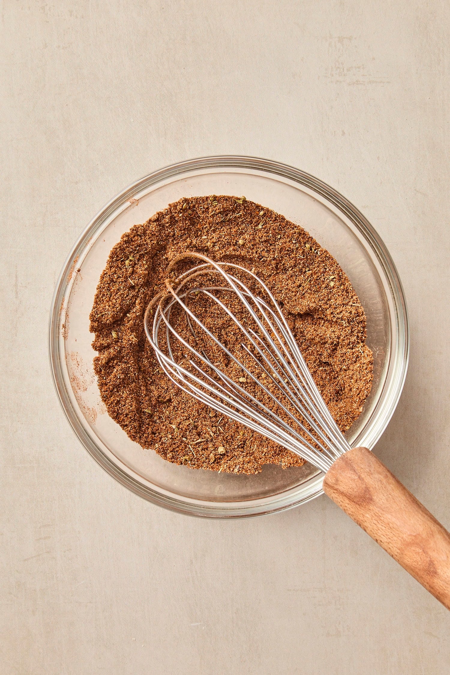 Glass bowl filled with whisked spice blend with whisk as well.