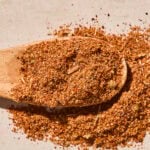 Wooden spoon with brown colored homemade taco seasoning blend in powder form.