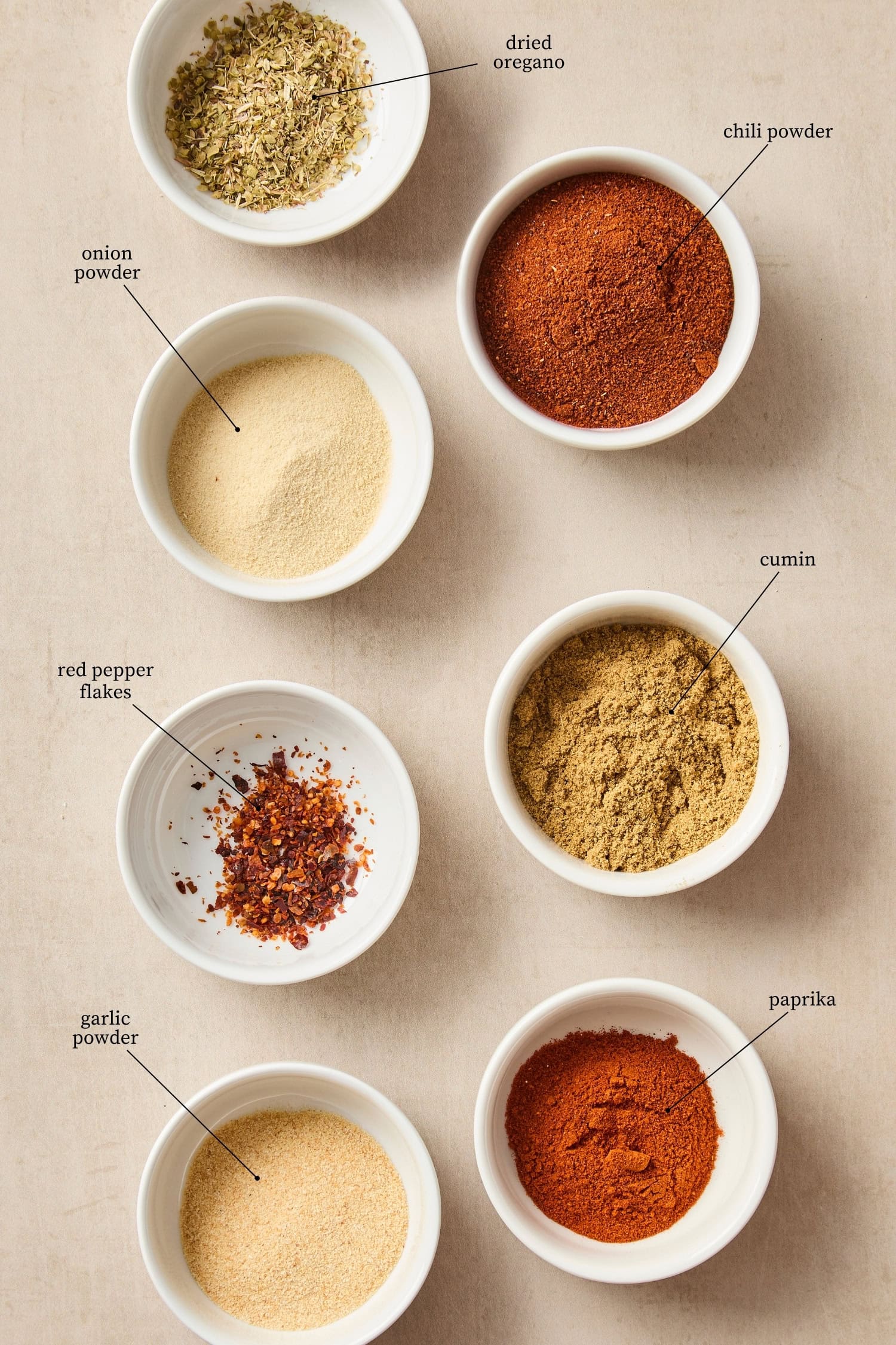 Tan surface with seven different spices to make a custom spice blend.