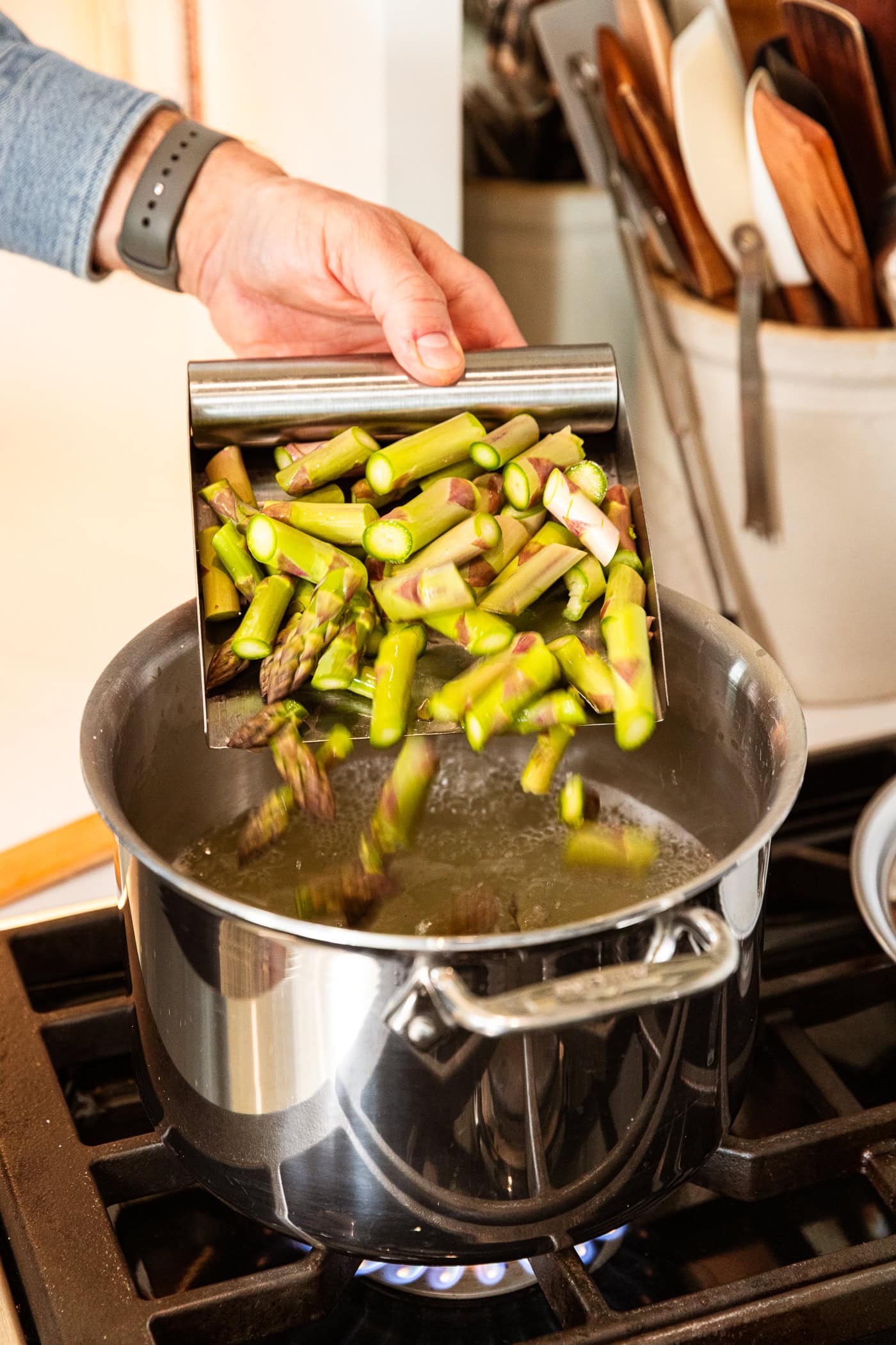 Adding asparagus to boiling water to cook.