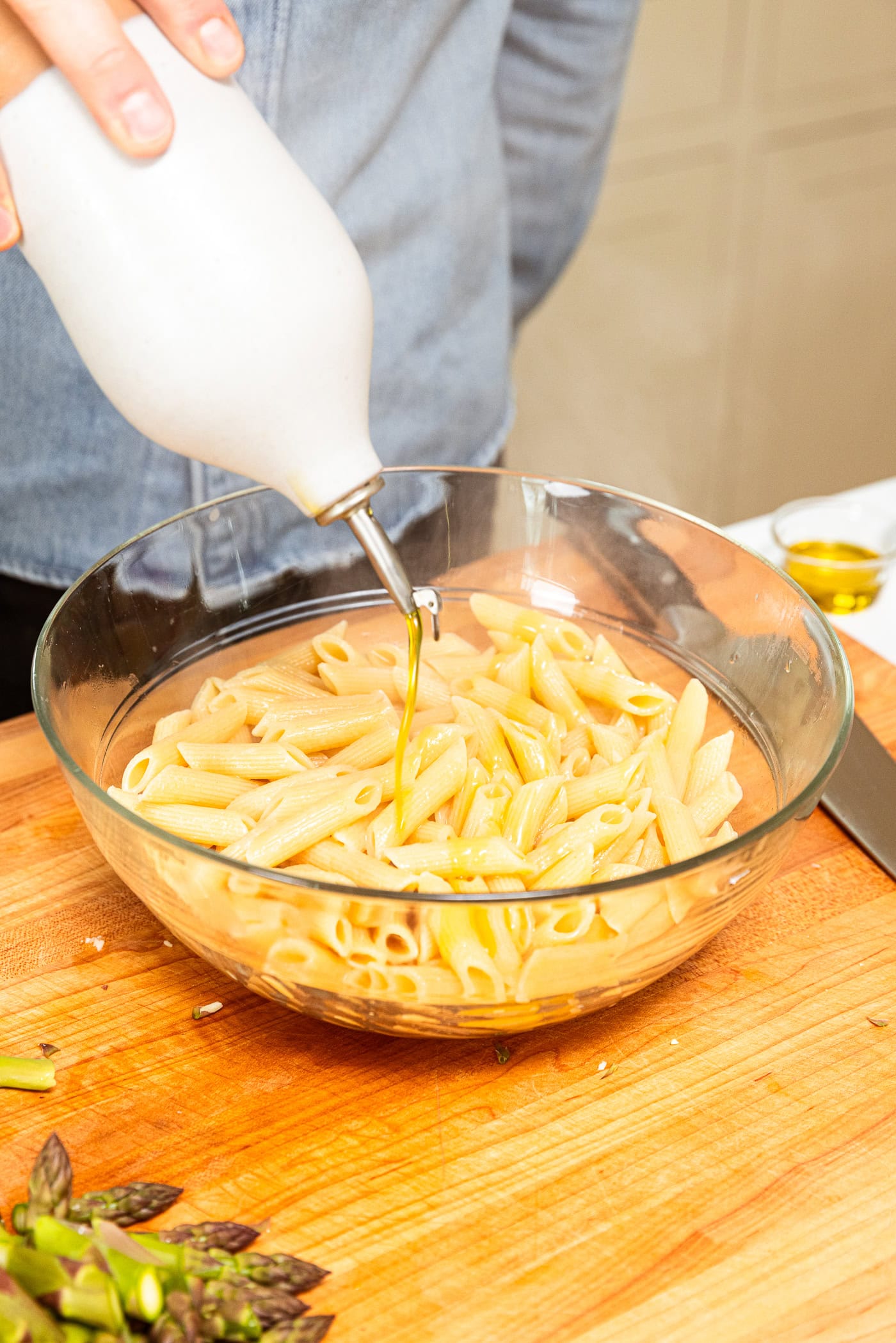 Adding olive oil to noodles after cooking.
