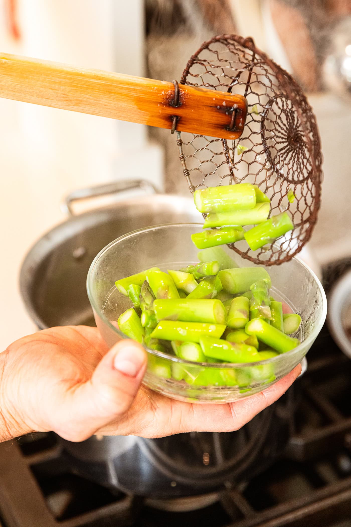 Asparagus pieces get added to a small bowl after cooking.