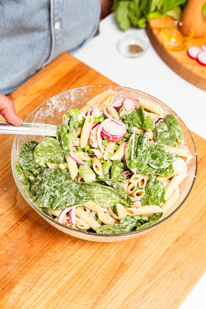 Primavera pasta salad getting mixed together.