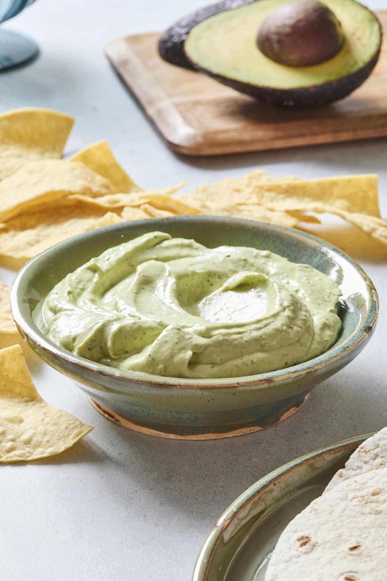 Stoneware bowl with avocado cream with chips in background.