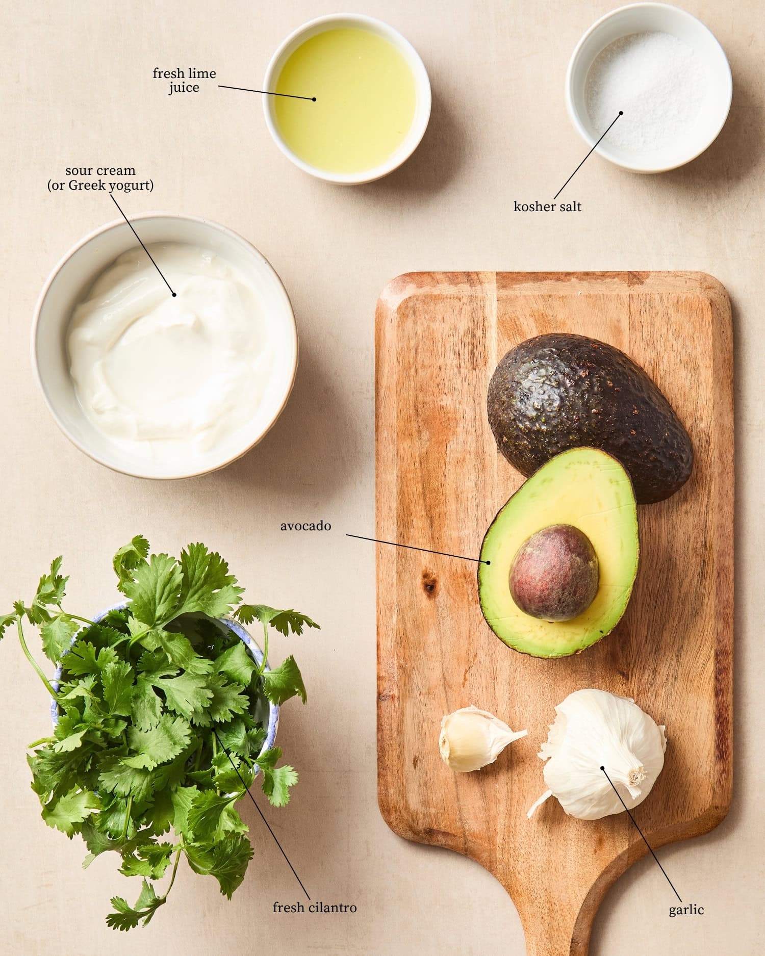 Surface with ingredients needed for an avocado crema including avocados, cilantro, spices, and more.
