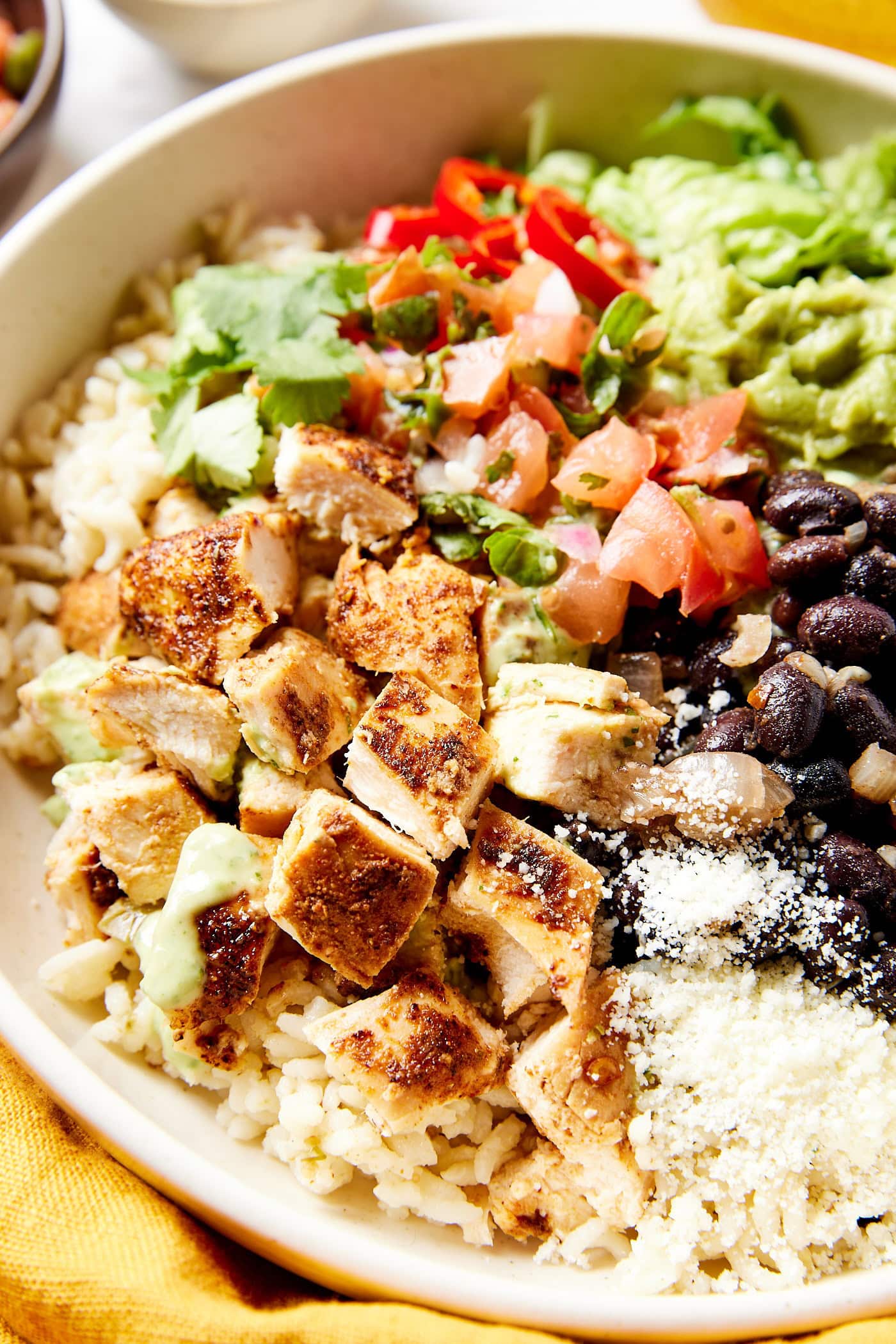 Cooked chicken in bowl with rice and beans and other toppings.