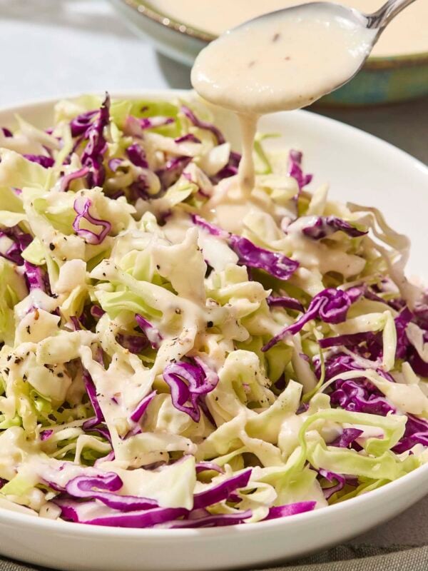 Cabbage with a creamy coleslaw dressing being poured over the top.